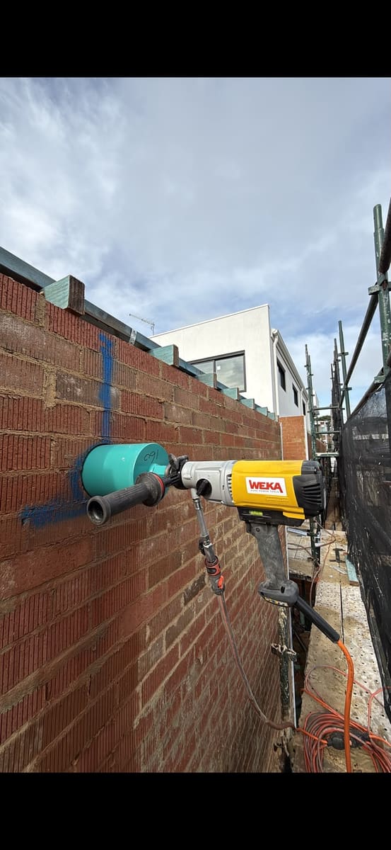 Cutting a brick wall with a hand saw on a Sydney site