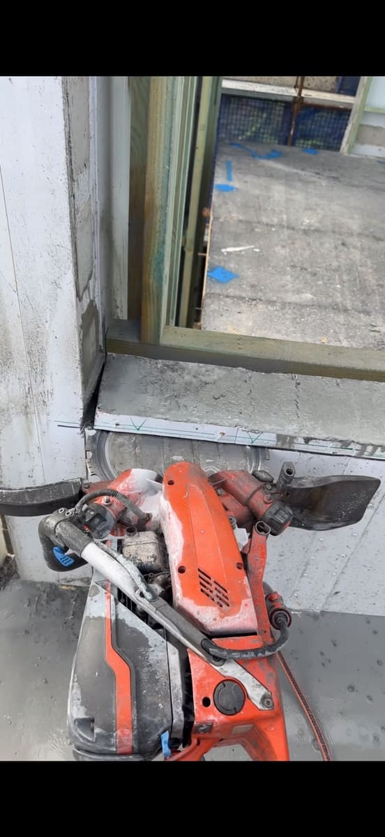 Hand sawing a window opening in a concrete wall