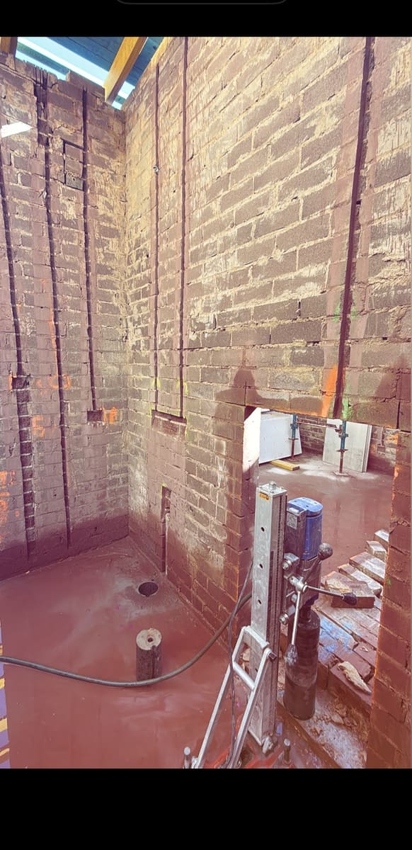 Core drilling rig set up in a brick room, holes cored in the floor