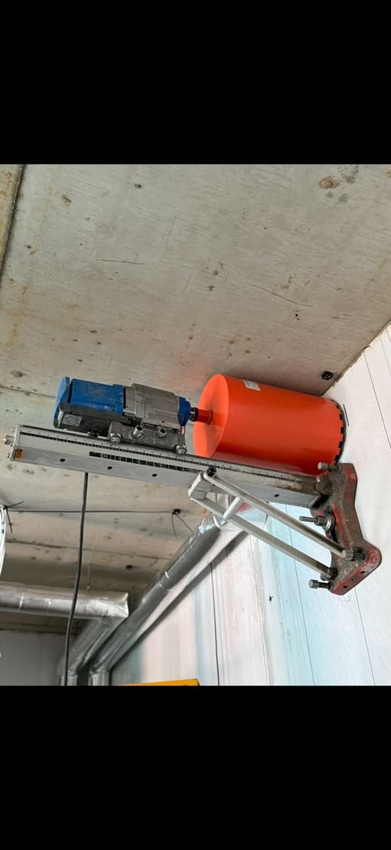 Core drilling rig anchored to a wall and running