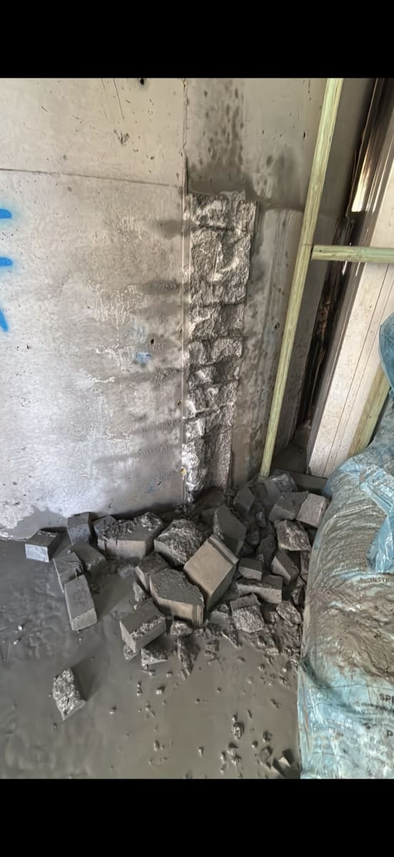 Wall section cut out and removed, rubble on the floor