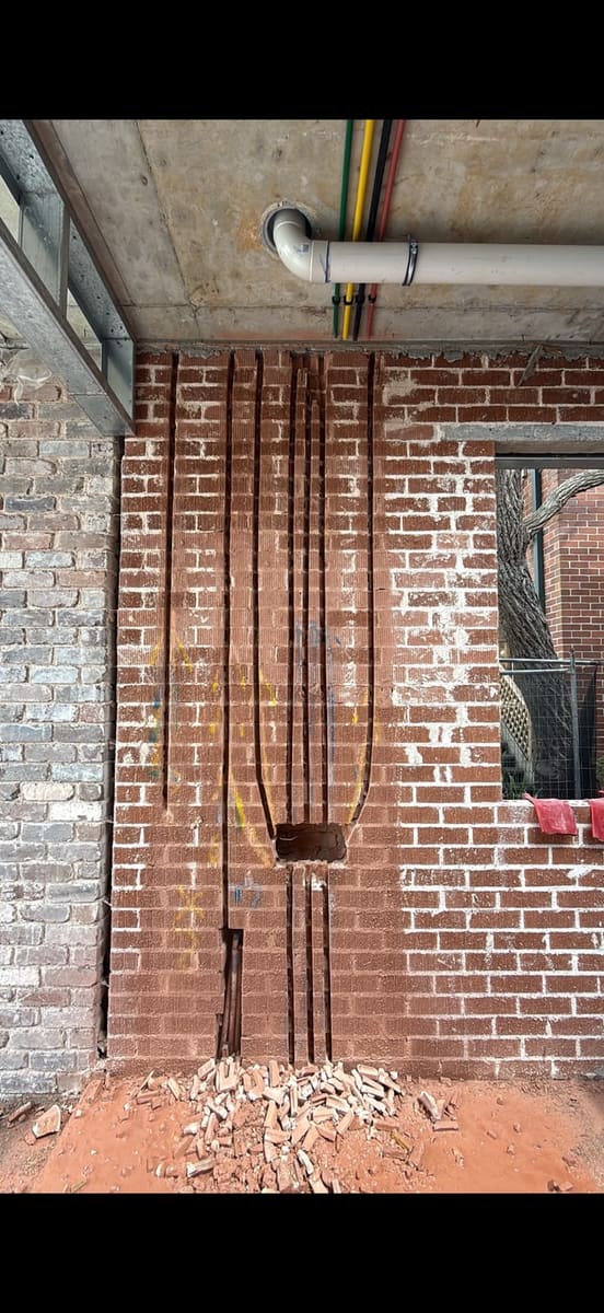 Wall chasing in a brick wall with electrical conduit run into the cut chases, Sydney